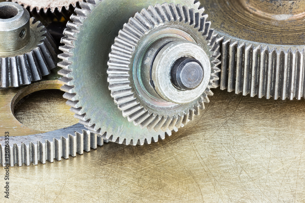 metal gears and cogwheels on scratched brass background. details for machinery closeup. metal gears and cogwheels on scratched brass background. details for machinery closeup.
