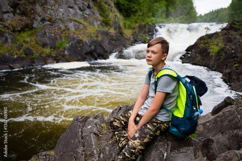 Teenager standing near the mountain waterfall
