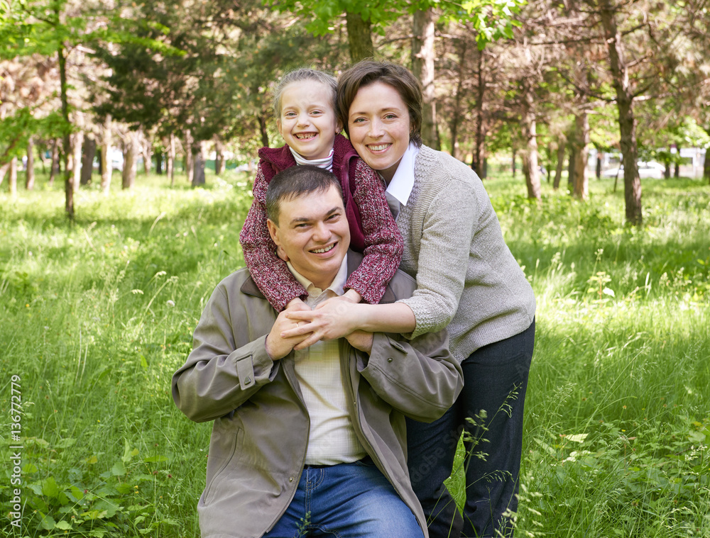 happy family with child in summer park, sunlight, green grass and trees happy family with child in summer park, sunlight, green grass and trees