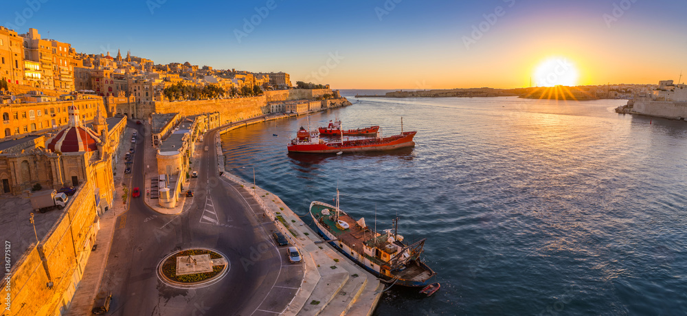 Valletta, Malta - Panoramic skyline view of Valletta and the Grand Harbor with beautiful sunrise, ships and clear blue sky