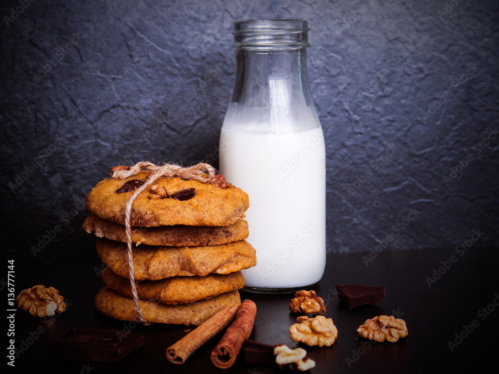 A glass of milk and healthy cookies on dark background A glass of milk and healthy cookies on dark background