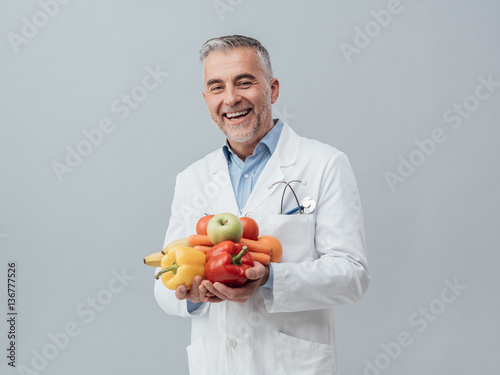 Smiling nutritionist holding fresh vegetables and fruit photo