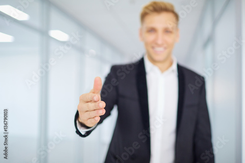 Concept welcome. Businessman holds out his hand and smiling in a modern office.
