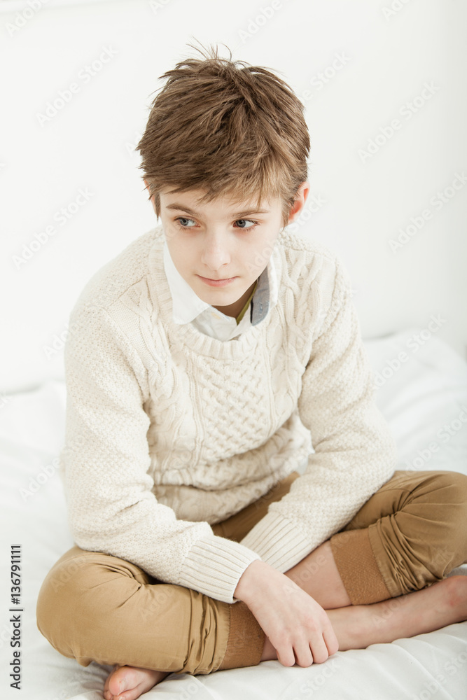 Thoughtful young boy sitting on his bed Thoughtful young boy sitting on his bed