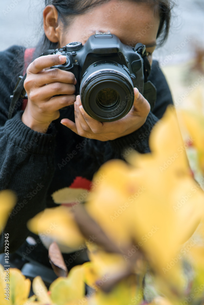 Obraz premium Woman with camera on meadow. Girl photographs of yellow flowers.