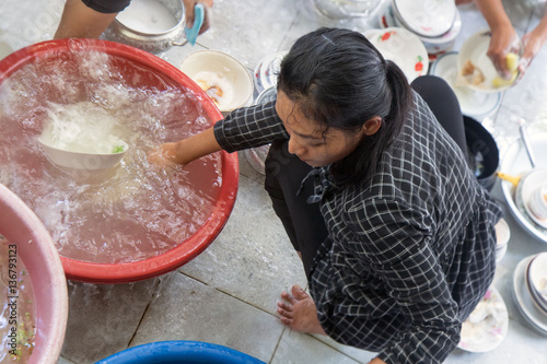 woman washes dishes in a basin on the floor