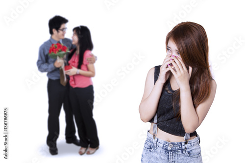Sad teenage girl looking at young couple
