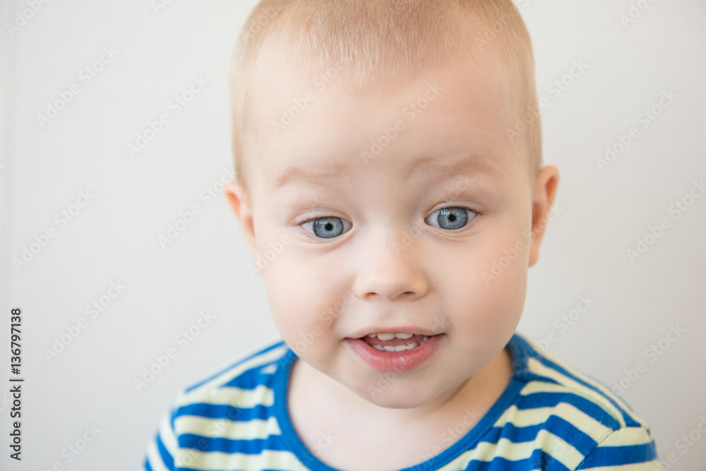 Little boy in striped t-shirt on a light background. Portrait. Close-up