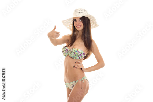 cheerful young woman with big natural boobs in swimsuit with floral pattern smiling and showing thumbs up isolated on white background