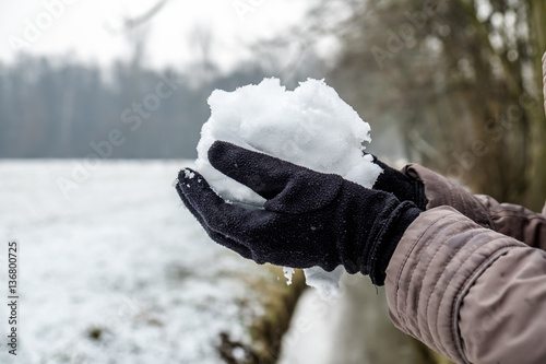 Hands with gloves holding snow
