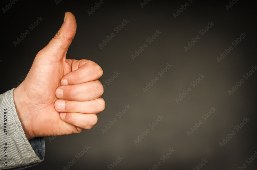 Hand mit Daumen nach oben / Positive Emotion, Hand mit Daumen hoch vor dunklem Hintergrund mit Textfreiraum. Hand mit Daumen nach oben / Positive Emotion, Hand mit Daumen hoch vor dunklem Hintergrund mit Textfreiraum.