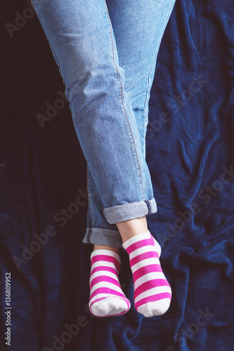 Woman in blue jeans and striped socks sitting on blue plaid