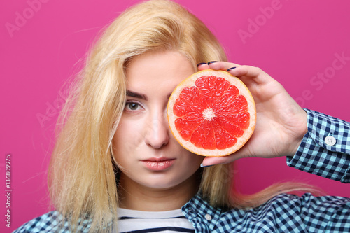 Young beautiful woman with grapefruit on pink background