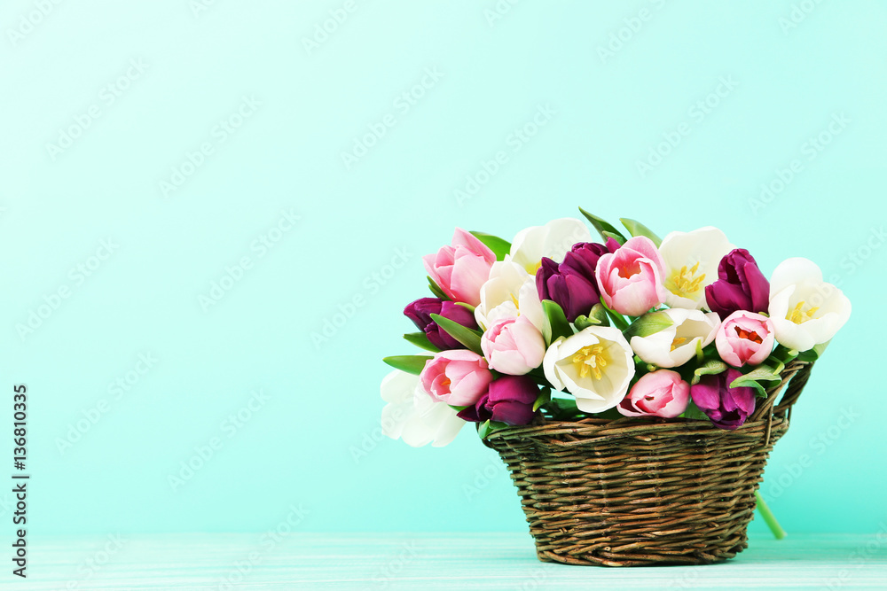 Obraz premium Bouquet of tulips in basket on green background