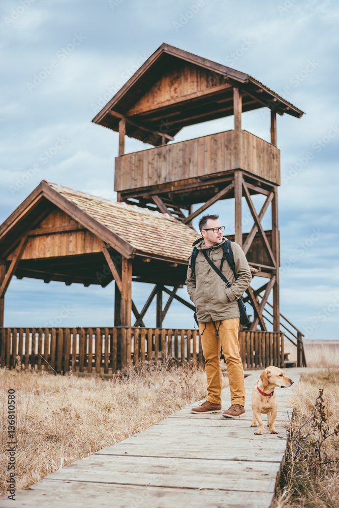 Hiker and dog standing on a wood walkway