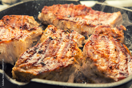 Fresh pork steak with spices cooking on teflon pan grill. Shallow depth of field.