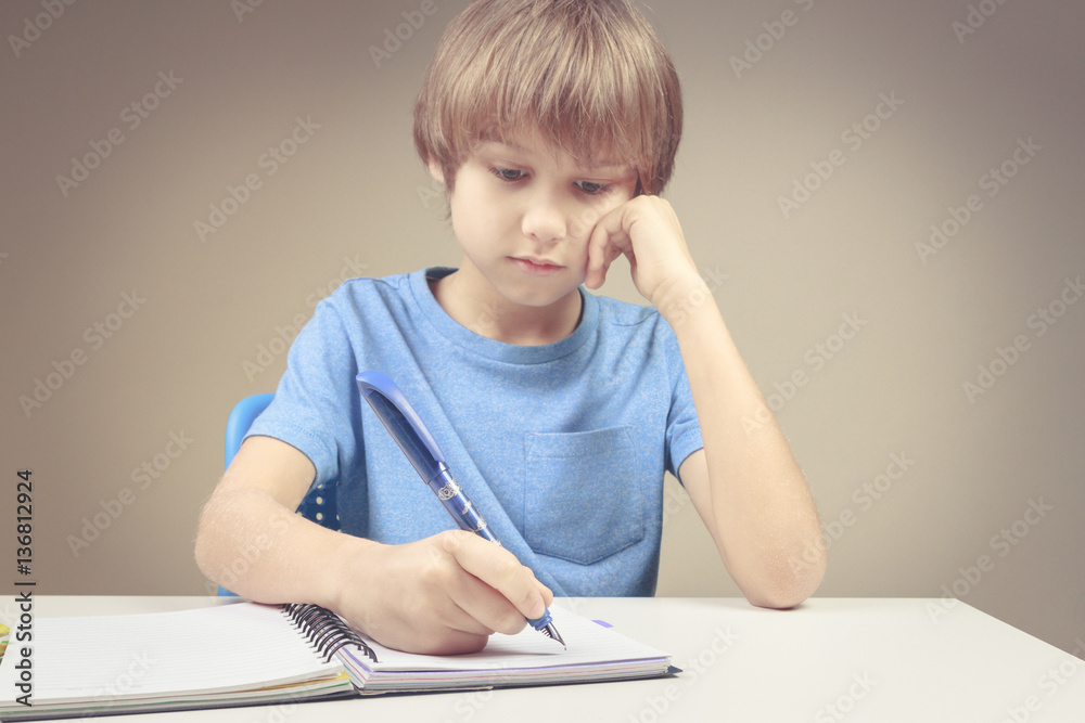 Boy writing on paper notebook. Boy doing his homework exercises Boy writing on paper notebook. Boy doing his homework exercises
