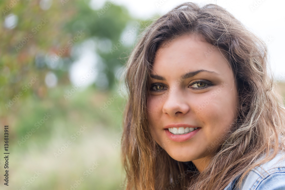 Portrait of smiling long hair brunette teenage girl outdoors closeup.