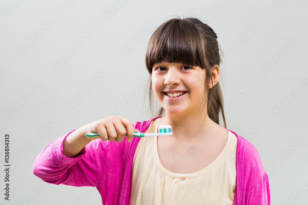Little girl holding toothbrush on grey background. Little girl holding toothbrush on grey background.