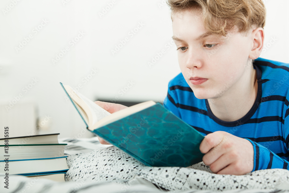 Young teenage boy studying at home on his bed Young teenage boy studying at home on his bed