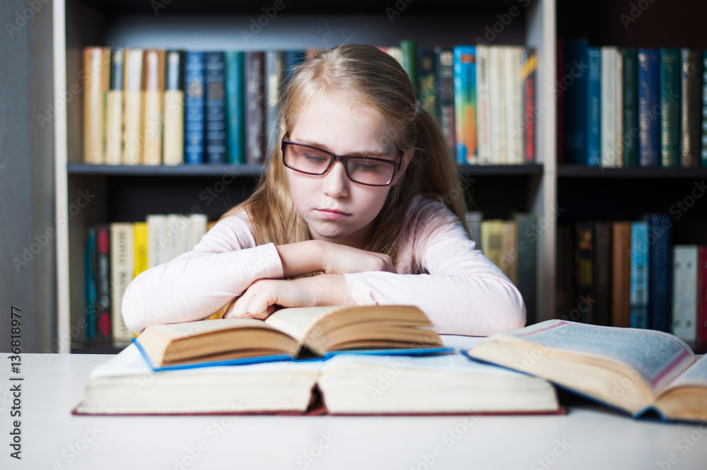 Angry and tired schoolgirl studying with a pile of books Angry and tired schoolgirl studying with a pile of books
