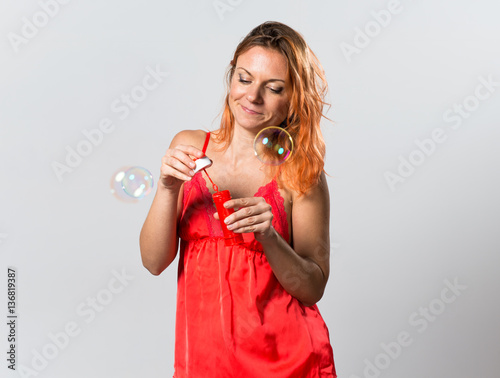 Beautiful woman with orange hair blowing bubbles