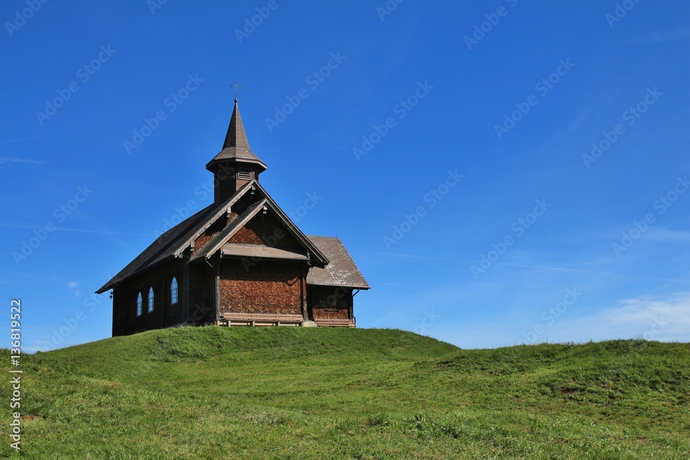 Timber chapel on a green hill in Stoos, Switzerland.