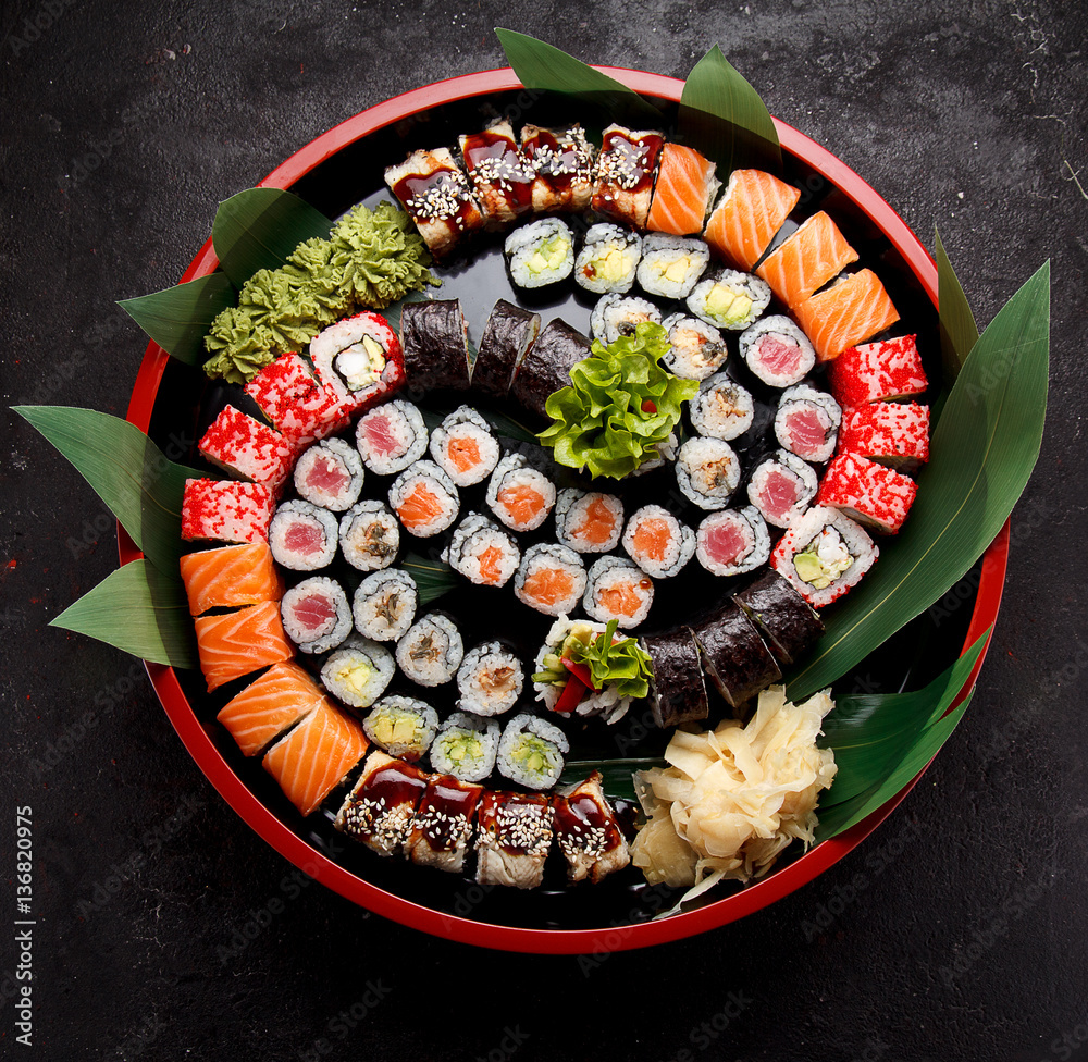 Japanese cuisine. Sushi set on a round wooden plate and dark concrete background. - obrazy, fototapety, plakaty 