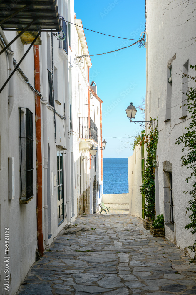 traditional old street of Cadaques village, Spain with view on blue mediterranean sea landscape