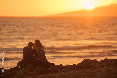 Couple in love taking pictures on the beach at sunset. 