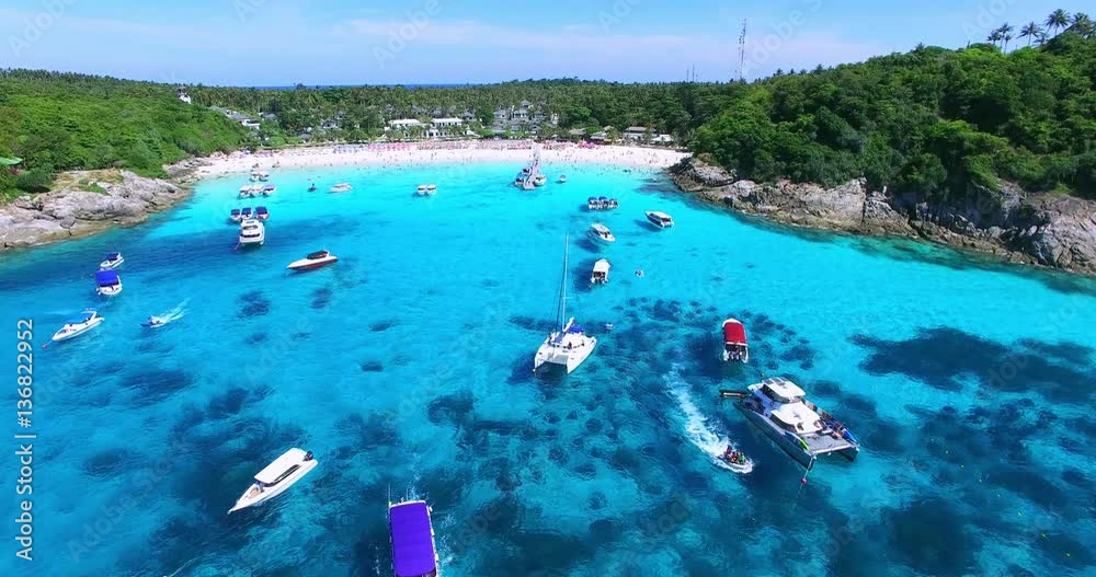 Racha Island Beach. Thailand, Phuket. Yachts , Catamarans and Boats sailing in crrystal clear blue water of ocean. Flying from ocean to sandy beach. Aerial view. 4K.