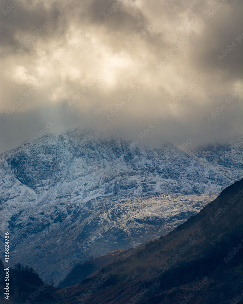 Dark and moody storm clouds over snowcapped Cumbrian mountains.
