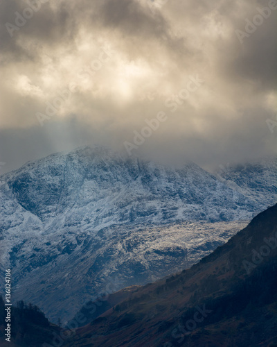 Dark and moody storm clouds over snowcapped Cumbrian mountains.