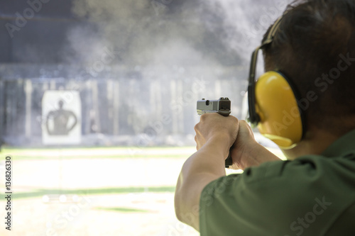 man firing automatic  pistol to target in shooting range