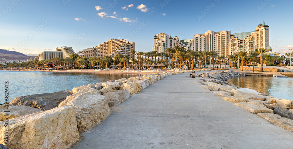 Evening at a public beach in Eilat - famous resort and recreational city in Israel. View from stone walking pier