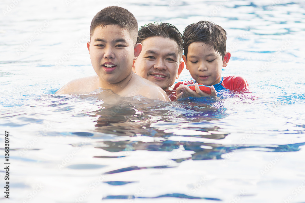 Happy dad and son swimming in a pool