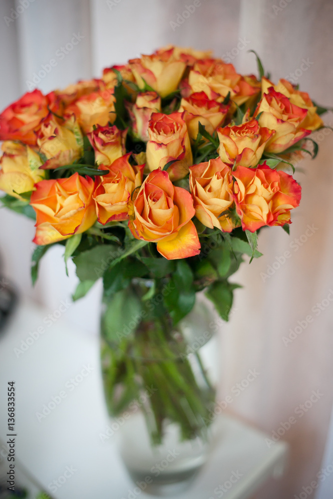 Naklejka premium a large number of bright golden orange roses. a large bouquet of roses. fire rose close-up. flower wall. small wall of roses
