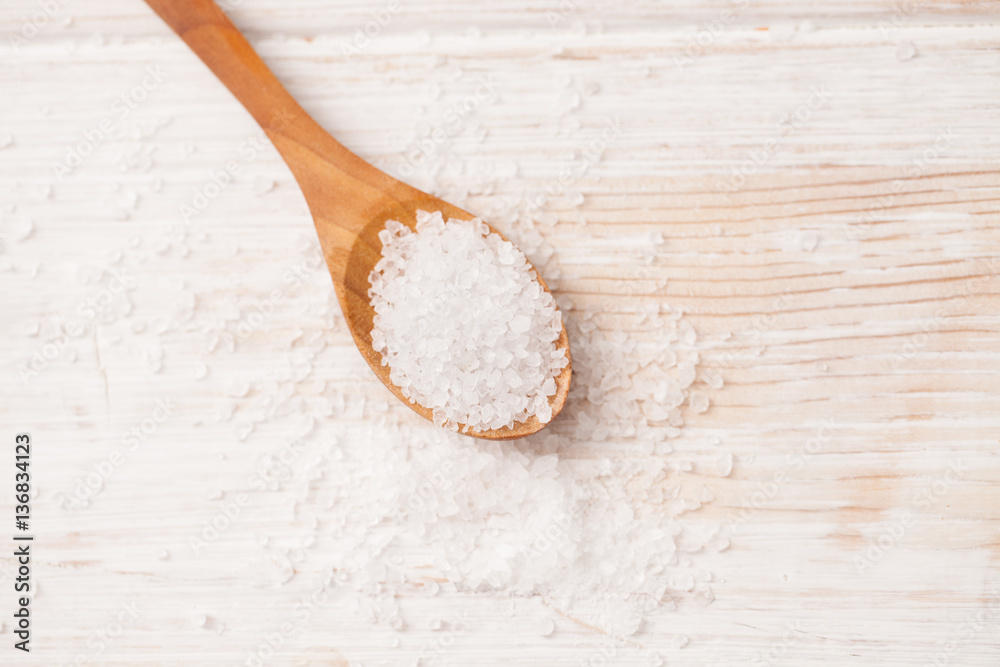 sea salt and wooden spoon on white wooden background sea salt and wooden spoon on white wooden background