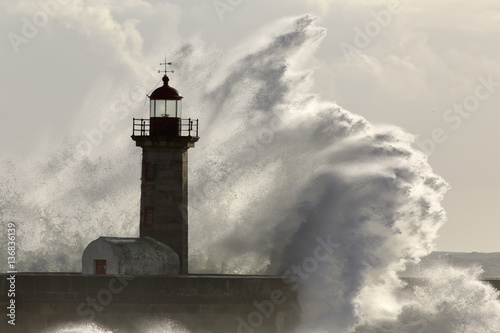 Big stormy sea wave splash over lighthouse