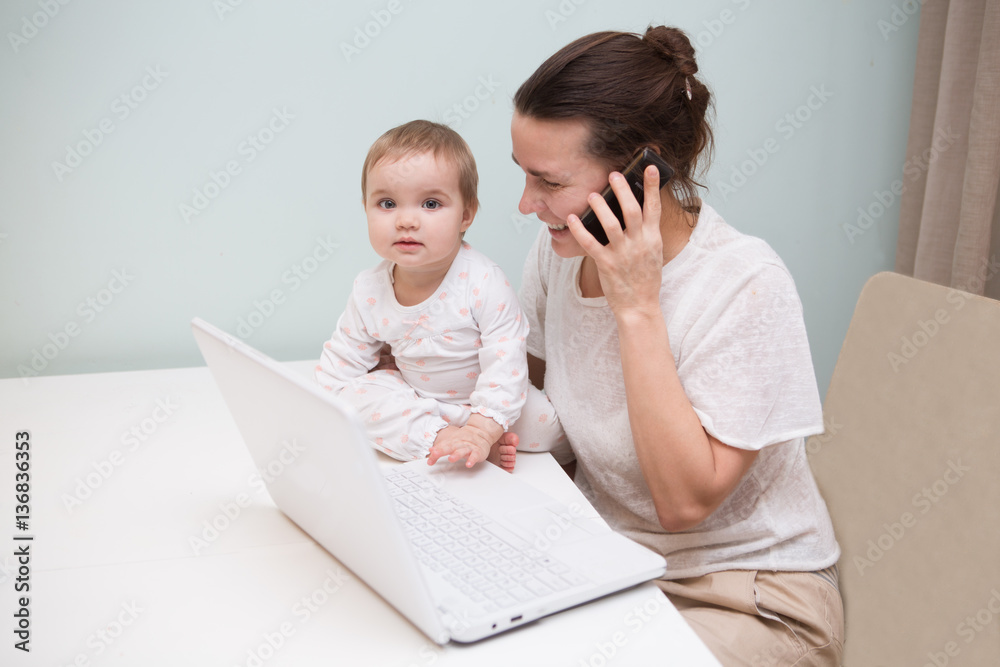 mom and baby. a young mother working with laptop in kitchen mom and baby. a young mother working with laptop in kitchen