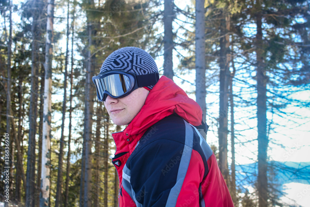 Skier in winter forest, mountains scene, portrait of young man in sunglass mask, ski resort concept Skier in winter forest, mountains scene, portrait of young man in sunglass mask, ski resort concept
