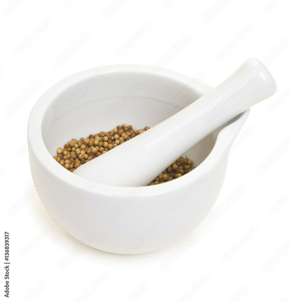 White porcelain set mortar and pestle with coriander grains. Iso White porcelain set mortar and pestle with coriander grains. Iso