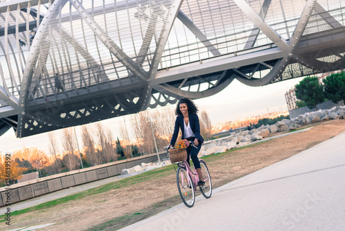 Business black woman riding a vintage bicycle in the city