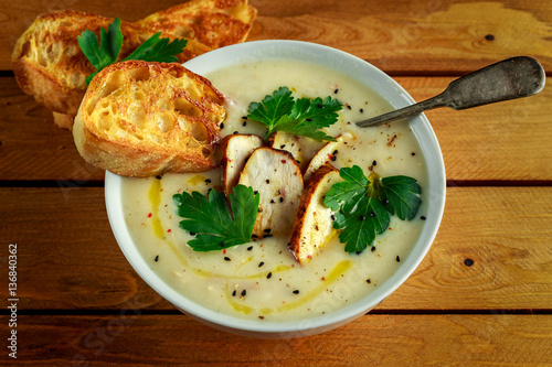 Creamy chicken soup with vegetables in bowl with chiabatta toast, parsley and nigela seeds sprinkle photo