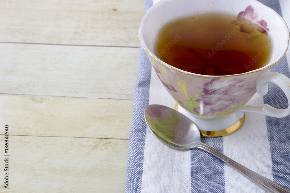 Fototapeta premium Cup of tea with napkin on light wood background 