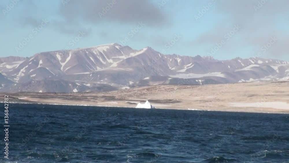 Mountains on shore in mountains on shore of Greenland in Arctic Ocean. Wilderness. Extreme tourism and travel in the cold polar north. Scenic coastline and blue water. Iceland. Mountains on shore in mountains on shore of Greenland in Arctic Ocean. Wilderness. Extreme tourism and travel in the cold polar north. Scenic coastline and blue water. Iceland.