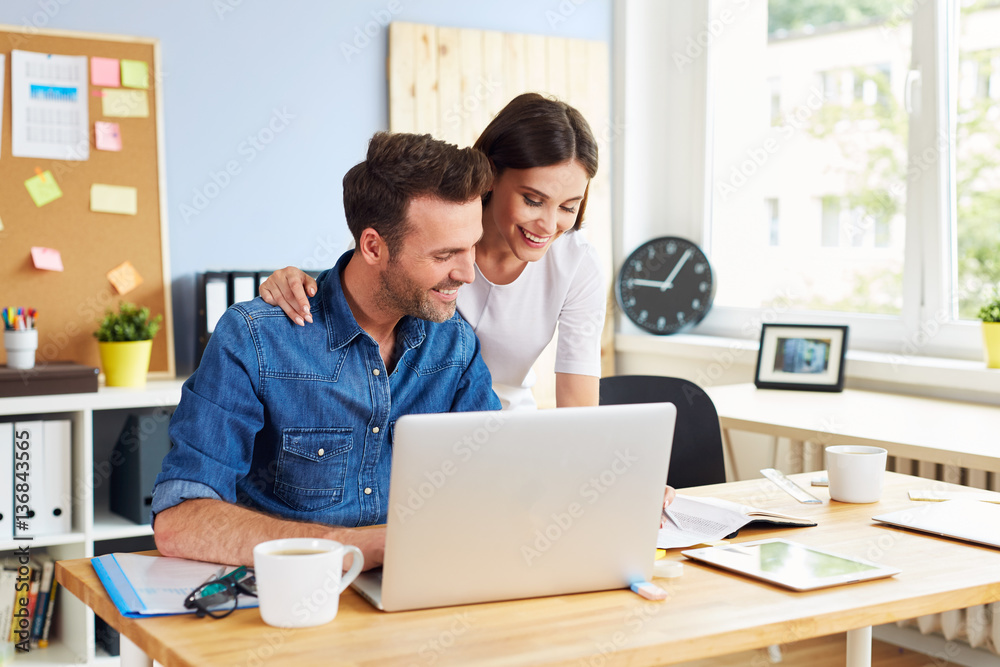 Happy couple running business together working with laptop from office Happy couple running business together working with laptop from office