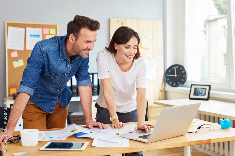 Happy couple running business together working on laptop at office Happy couple running business together working on laptop at office