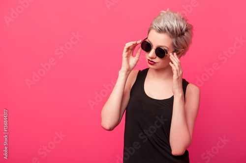 Fashion girl in black shirt and sunglasses on pink background
