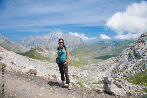 brunette sport hiking or trekking woman with green shirt brown trousers posing looking over valley and mountain in Picos de Europa natural park in Cantabria Spain 